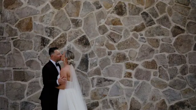 Stone wall kiss: Carlee & Ryan's wedding at CedarCreek Estate Winery, Kelowna. Still from the Pixel Pro wedding film.